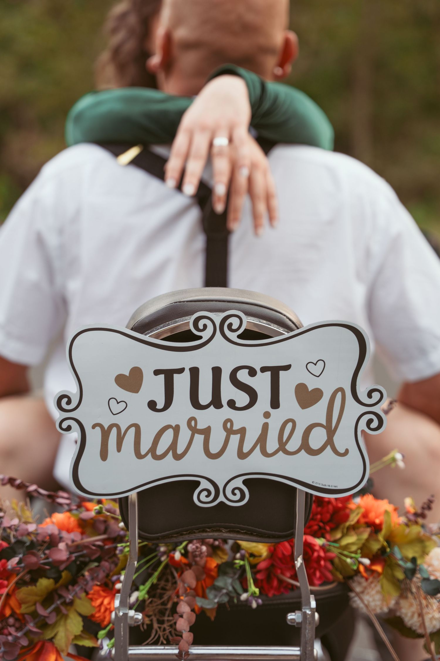 A decorative 'Just Married' sign with floral arrangements in autumn colors.