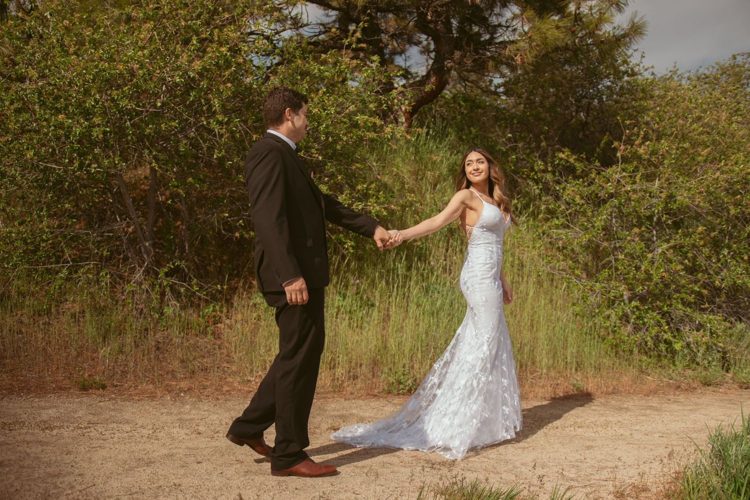 A romantic dance sequence captured on a dirt trail with mountain views in the background.