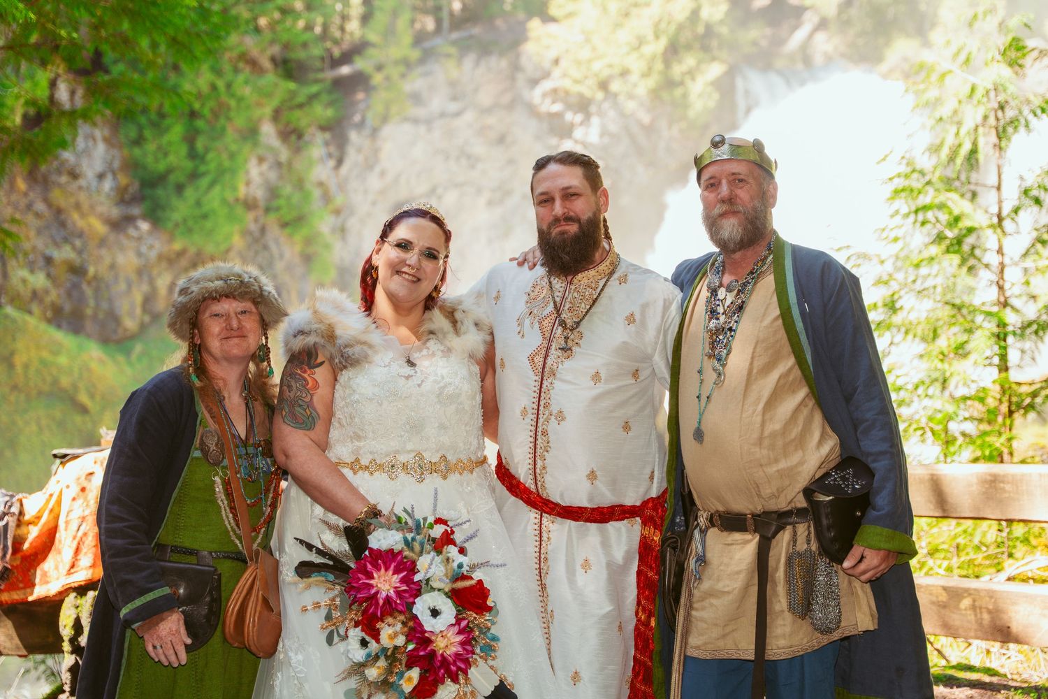 Group photo of wedding party members in coordinated burgundy and neutral attire outdoors.