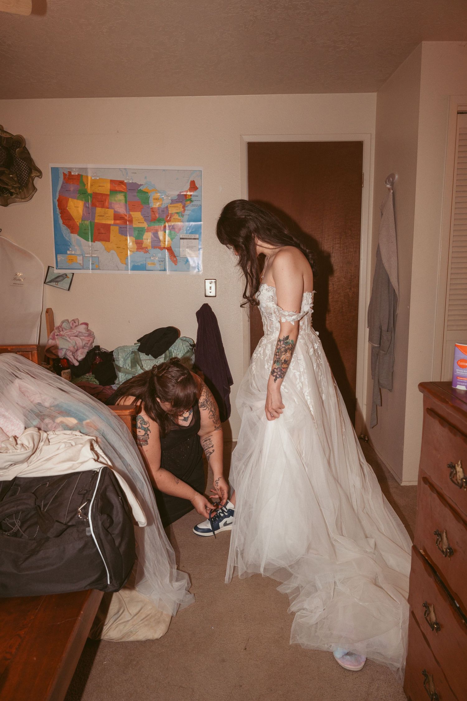 Bride getting dressed and prepared in room with colorful wall map.