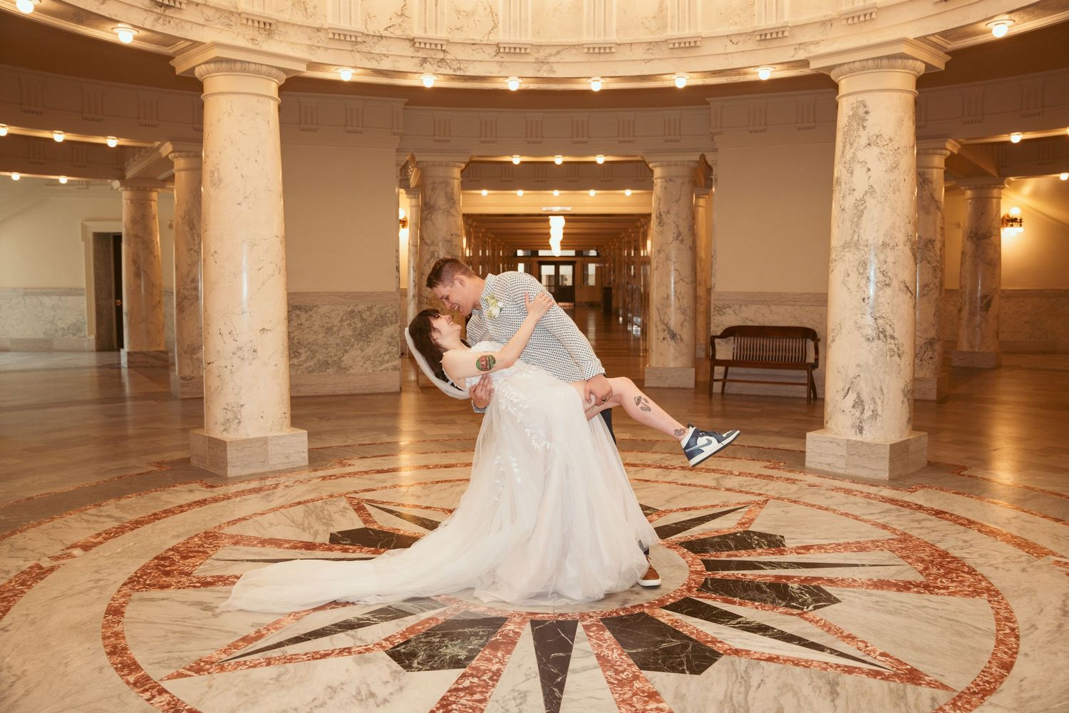 Elegant marble ballroom with ornate floor patterns and columns for a wedding celebration.