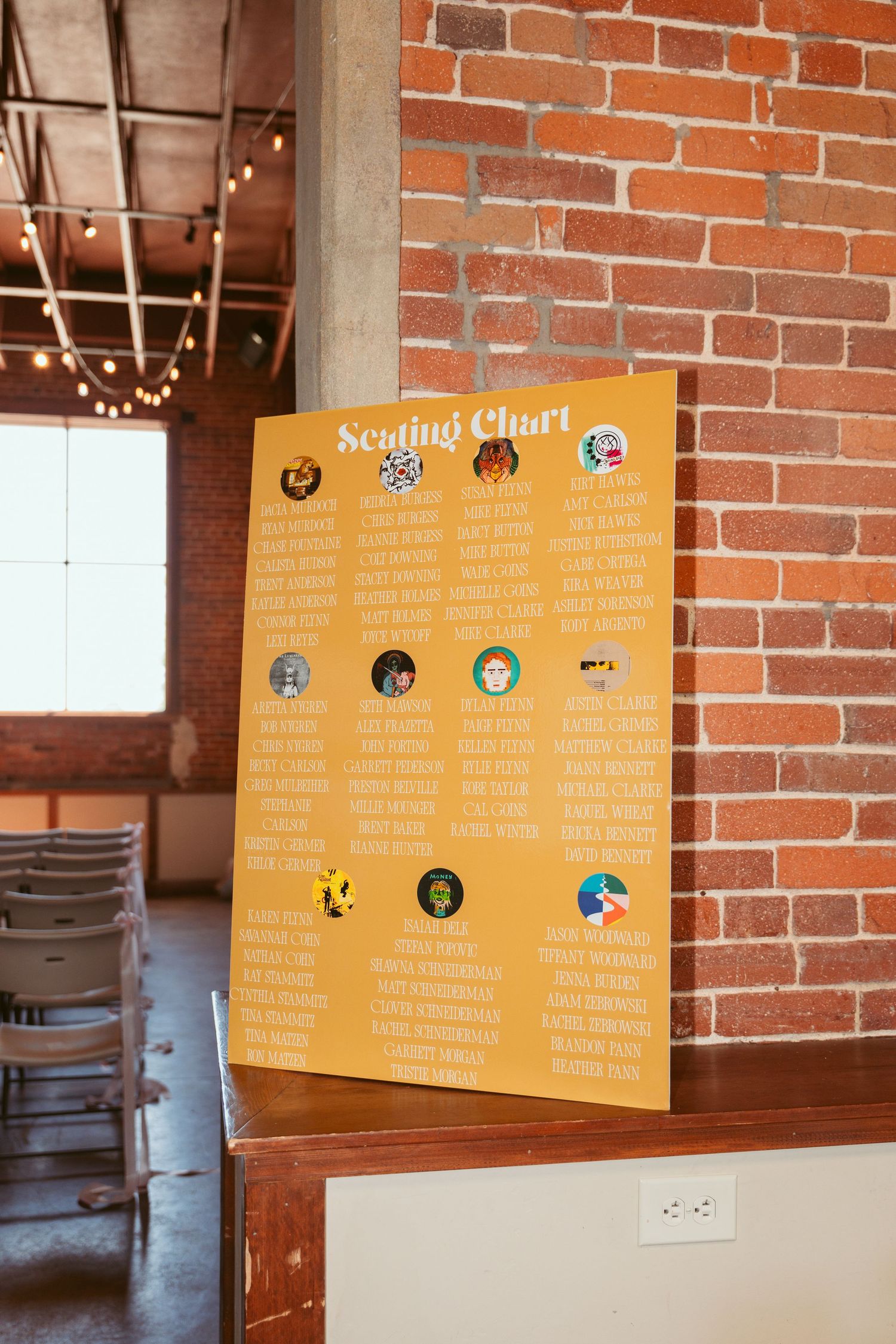 Yellow seating chart displayed on brick wall in rustic wedding venue.