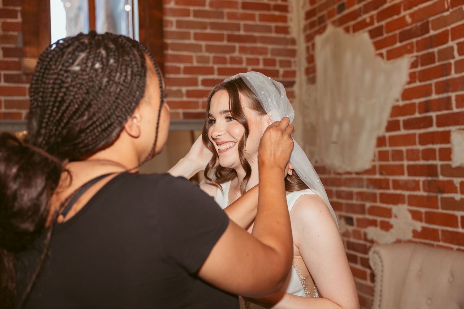 Close-up of wedding dress being fastened in rustic brick venue.