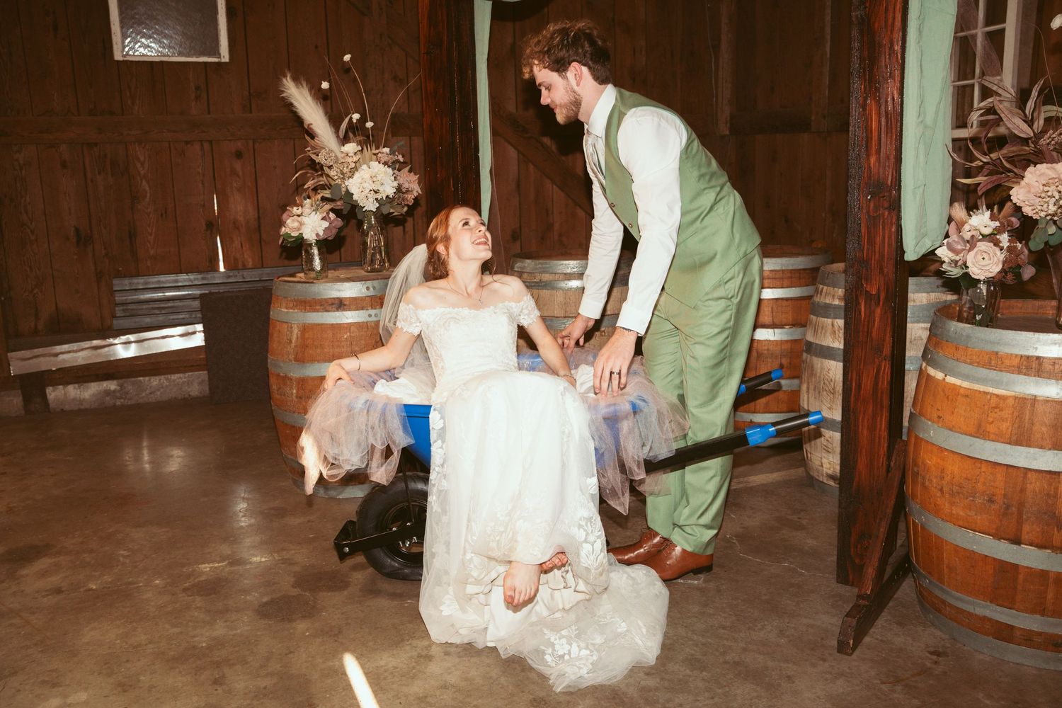 Wedding guests dance and celebrate on a wooden dance floor under twinkling lights.