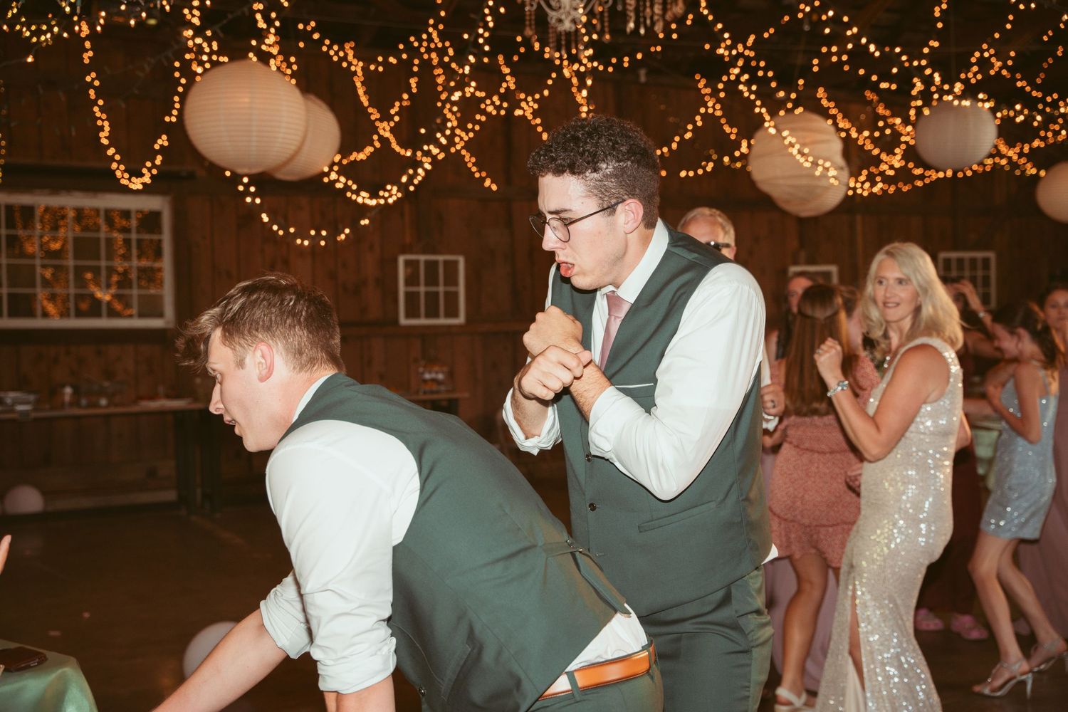 Guests enjoying a lively dance floor under romantic string light decor at a wedding celebration.