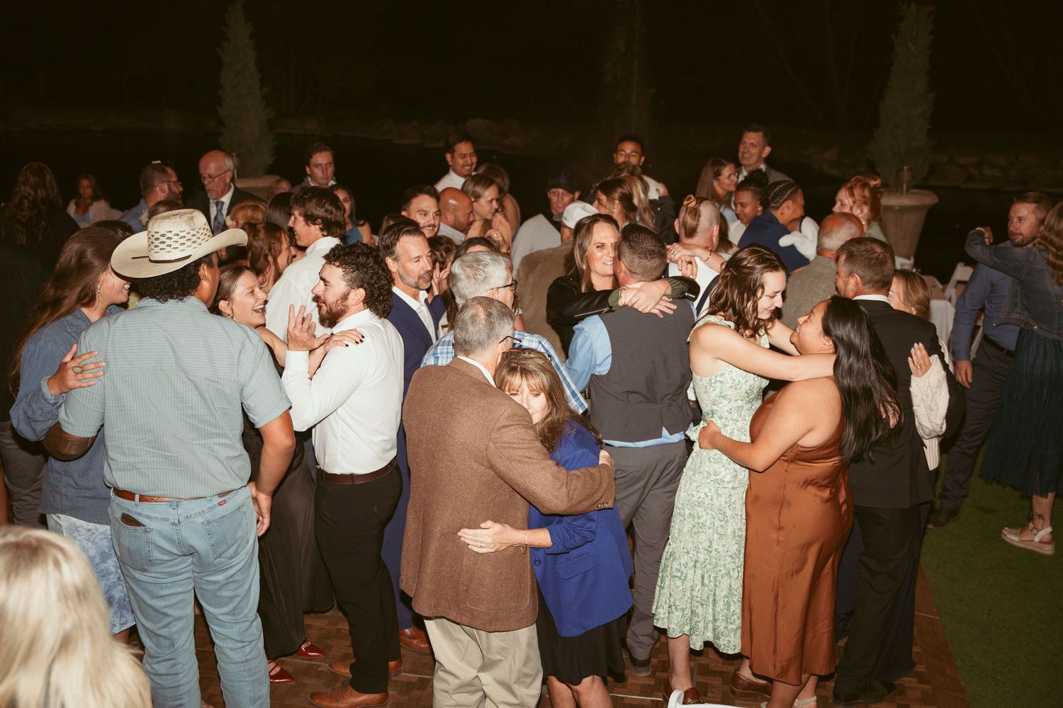 Crowd of party guests dancing together at an outdoor evening celebration.