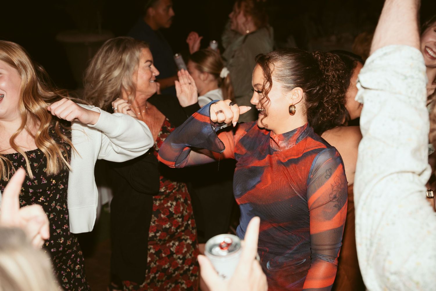Energetic dancing and celebration at a dimly lit outdoor wedding reception.