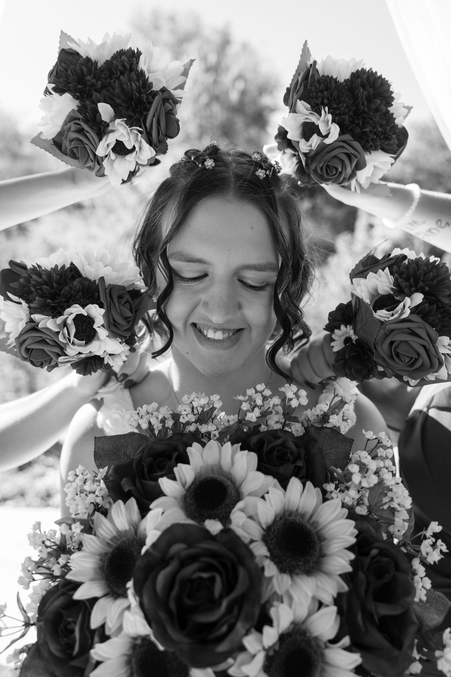 Black and white portrait with floral crown and bouquet featuring roses and sunflowers.
