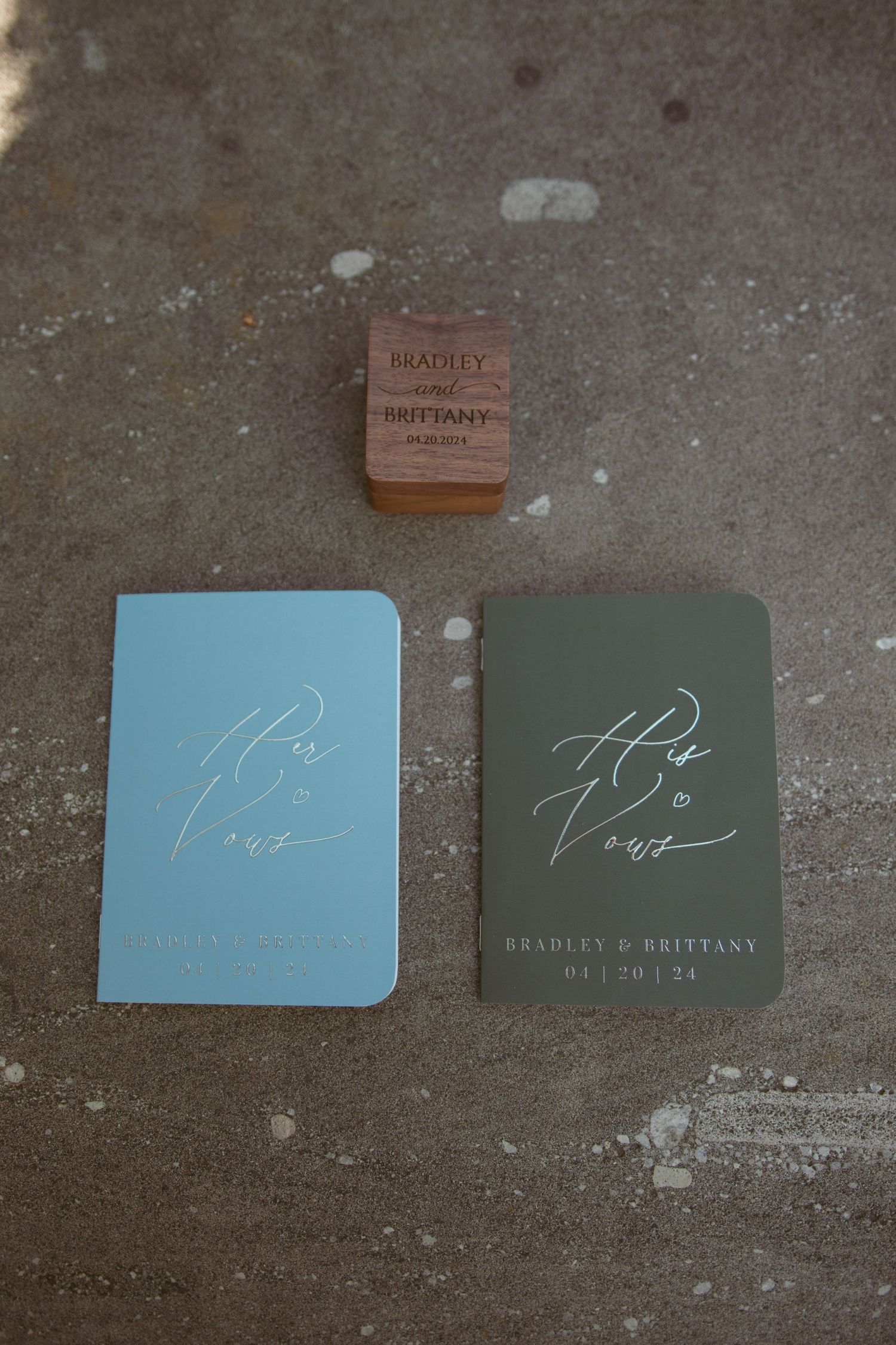 Wedding invitation vow books in light blue and dark green with wooden accent.