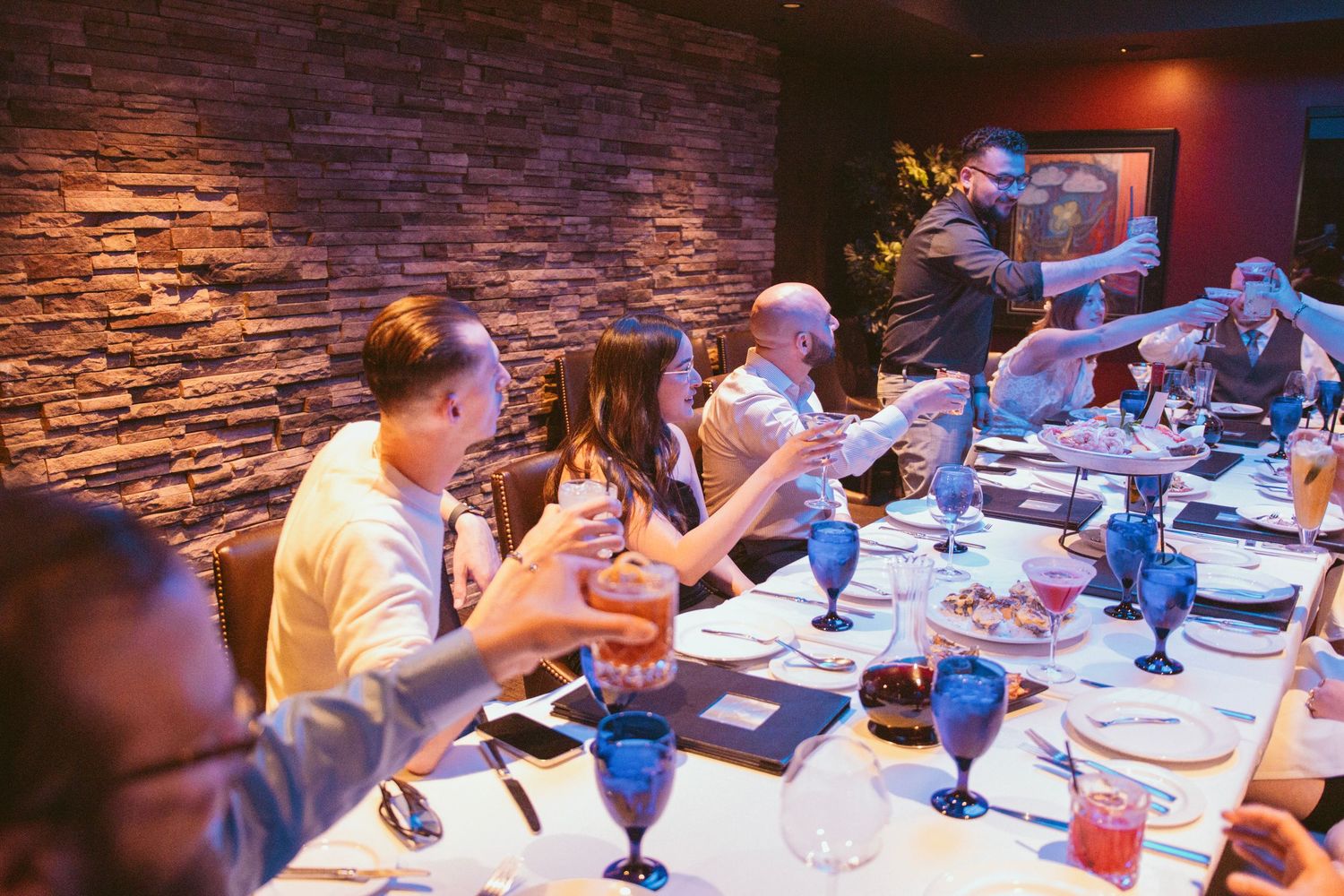 Wedding reception dinner setup with stone accent wall and blue mood lighting.