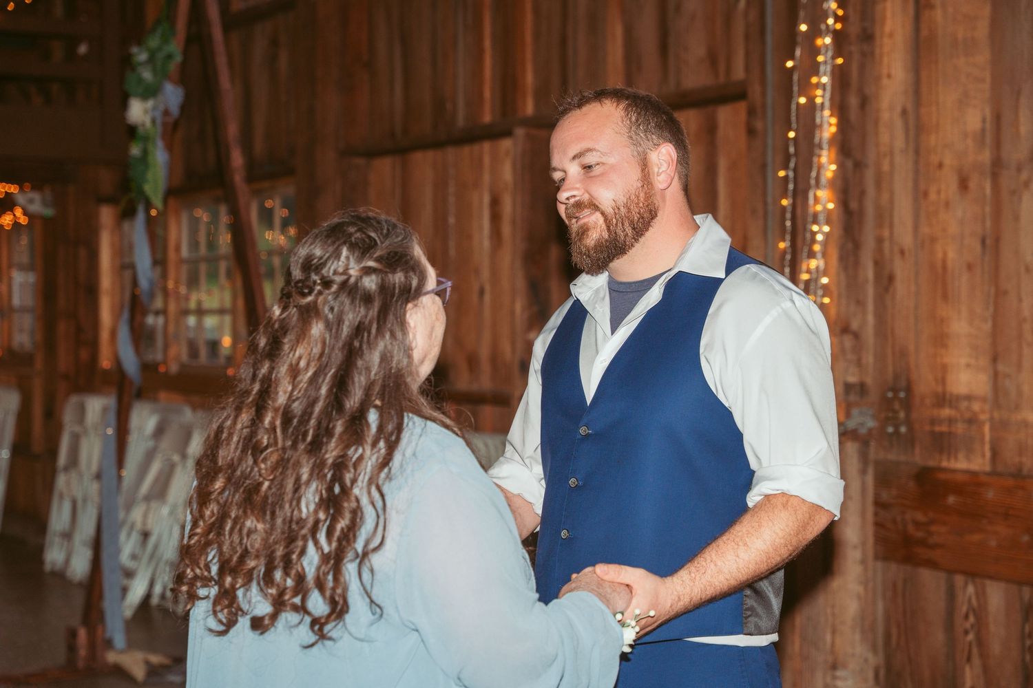 Dancers twirl and move across a wooden barn floor during a celebration.