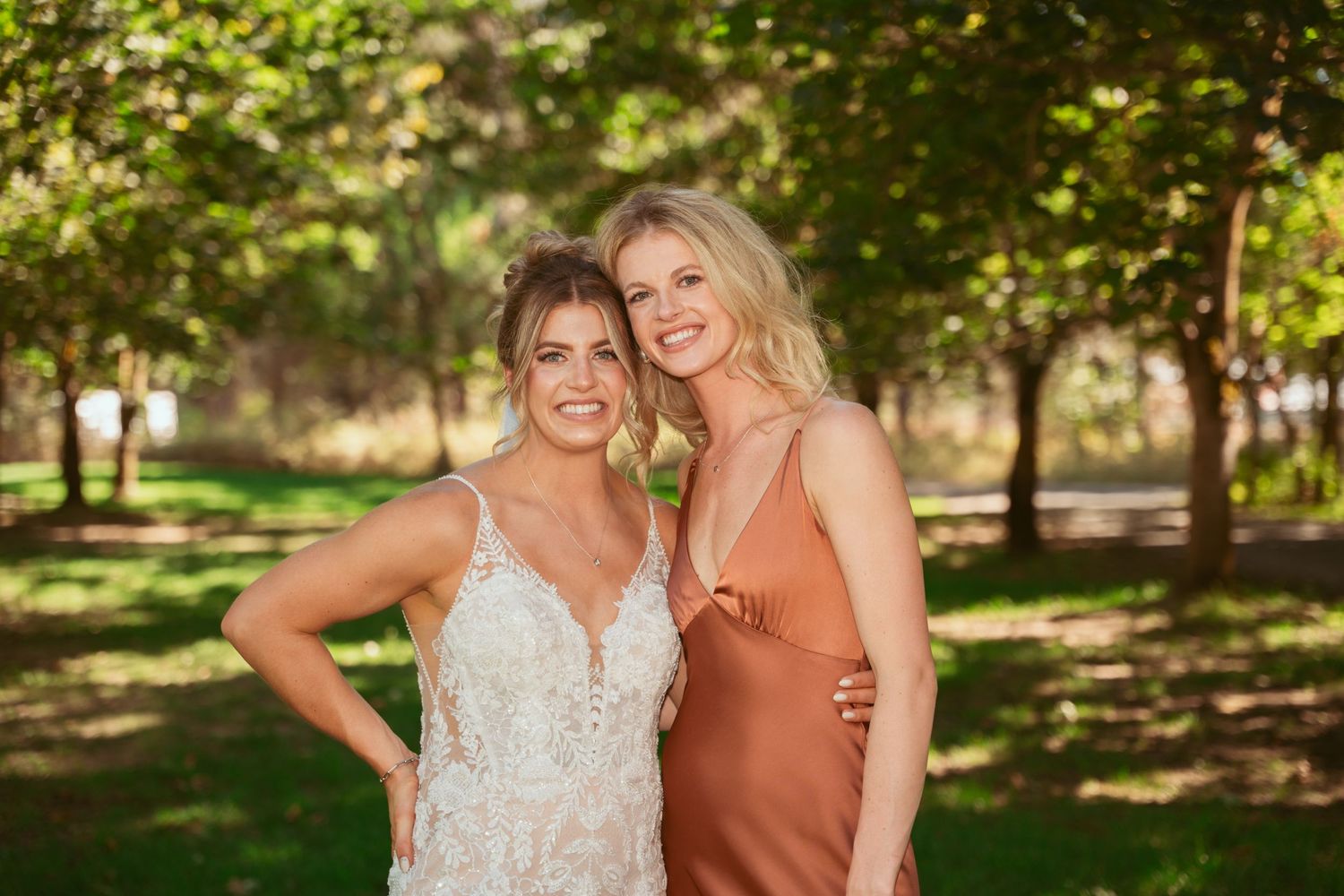 Wedding party members pose for photos in a scenic outdoor garden setting.