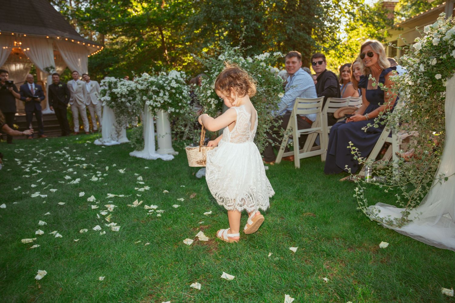 Wedding celebration in progress on a beautiful garden lawn with scattered flower petals.