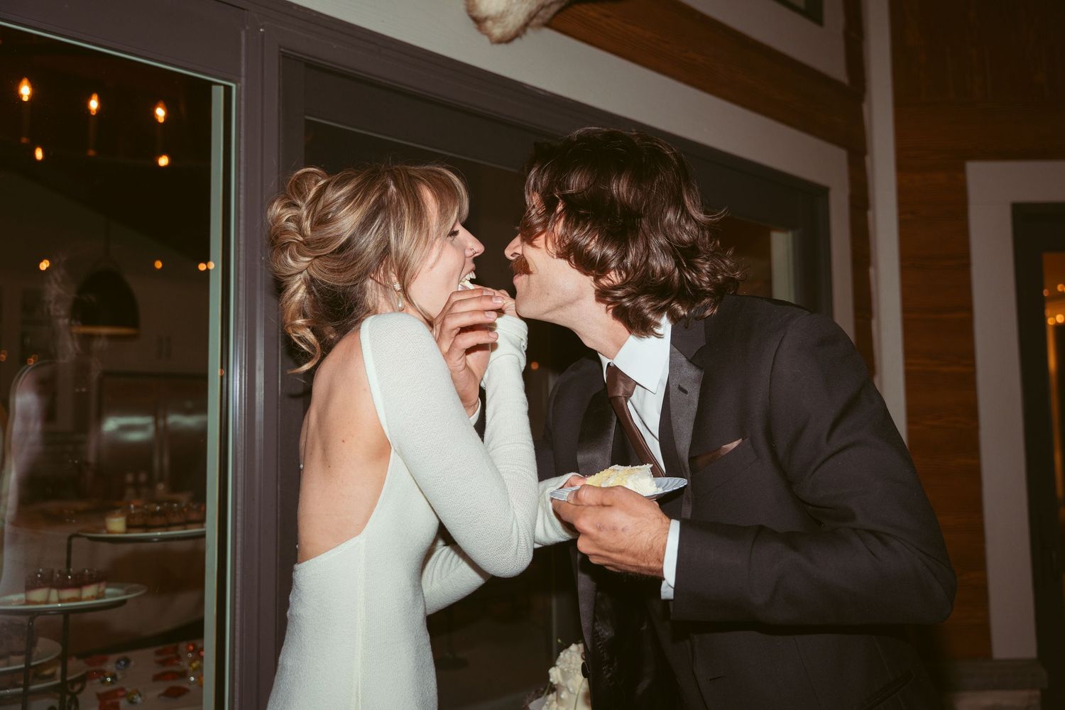 A couple shares an intimate dance moment at their wedding reception with warm lighting in the background.