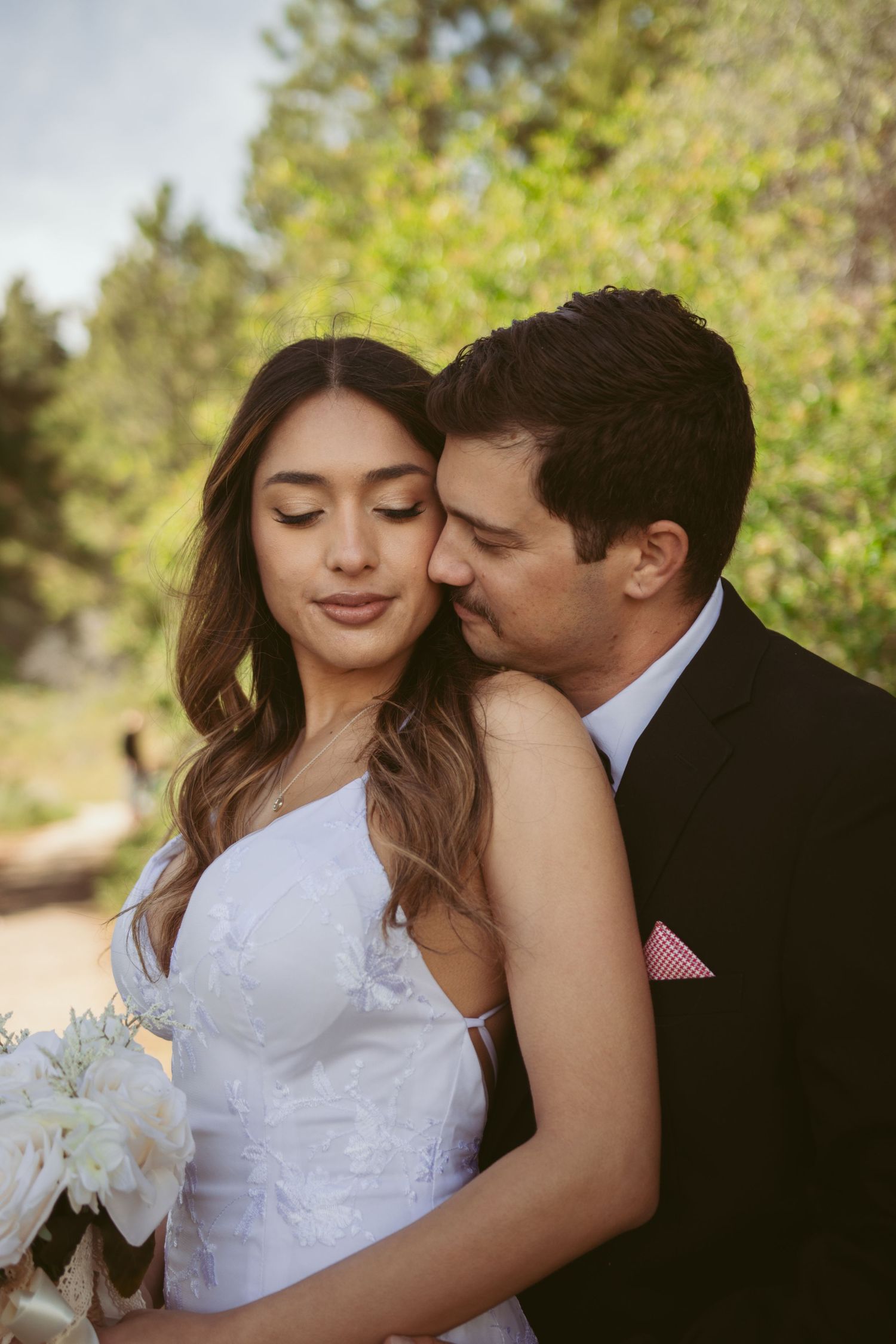 An intimate moment between newlyweds with spring foliage in the background.