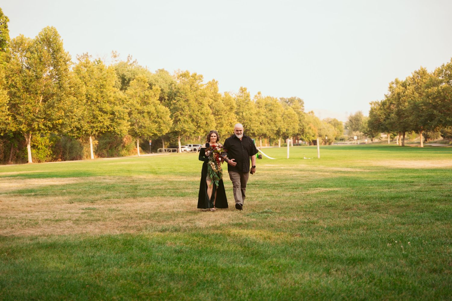 Wide angle view of an outdoor wedding venue setup in a grassy field during golden hour.