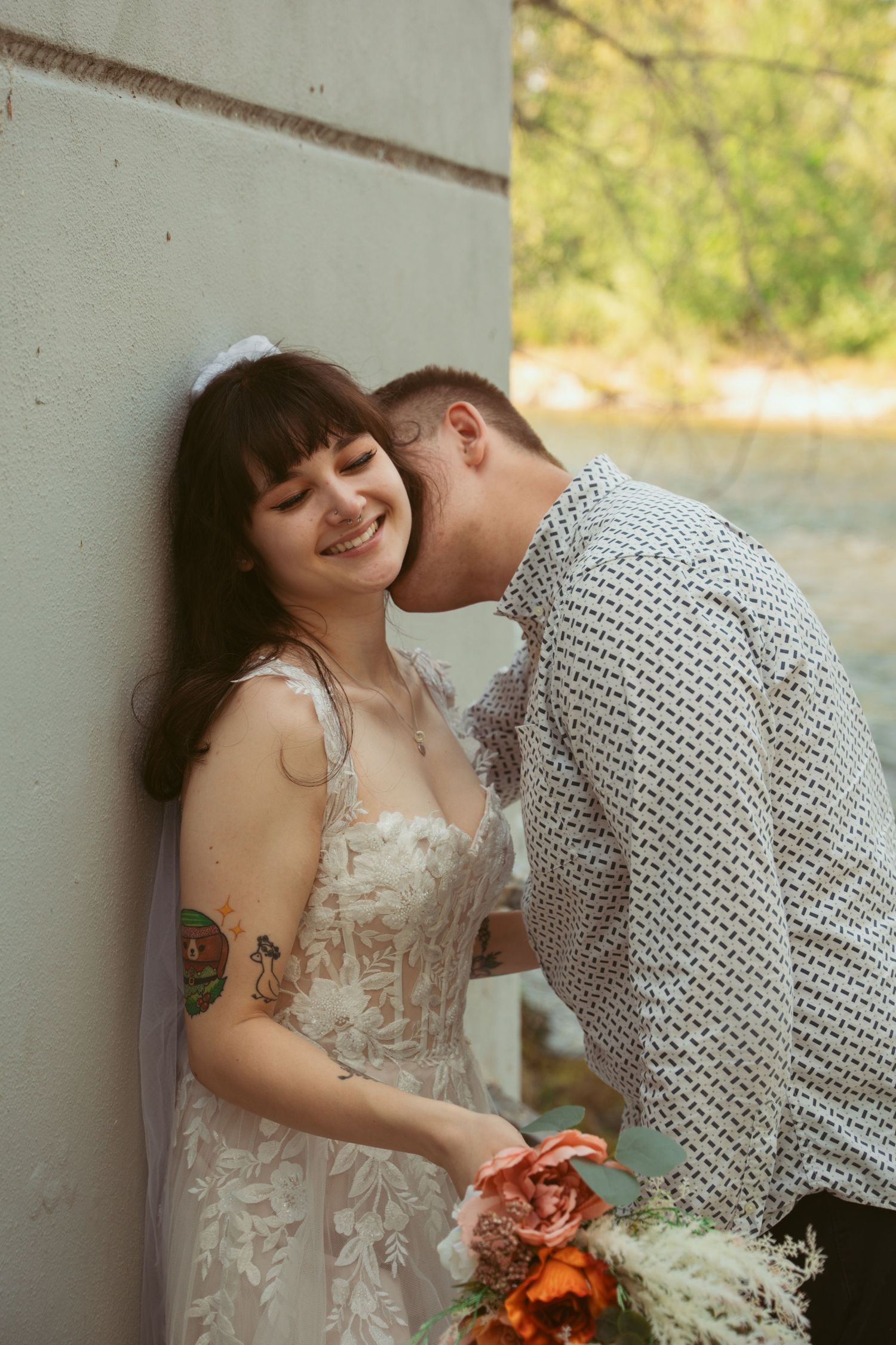 Romantic wedding couple sharing an intimate moment against a wall in formal attire.