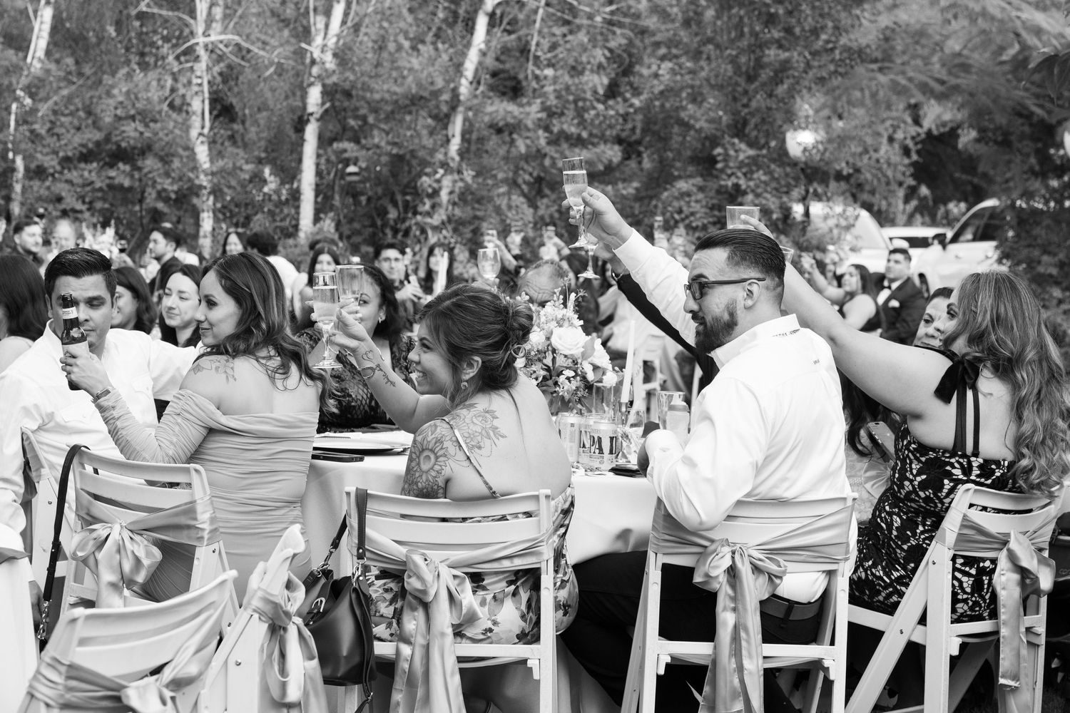 Wedding guests seated in white chairs during outdoor ceremony.