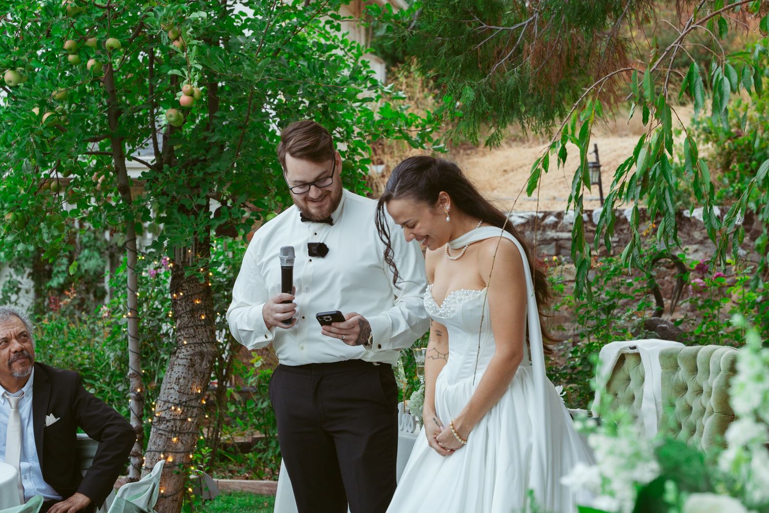 Wedding party enjoys candid moments in lush garden setting.