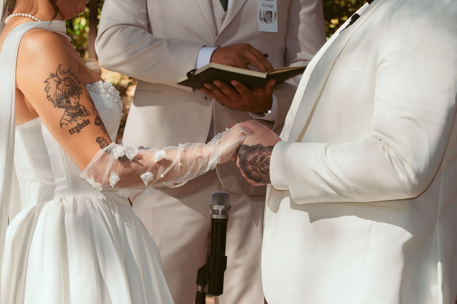 Close-up of couple exchanging rings during outdoor wedding ceremony.