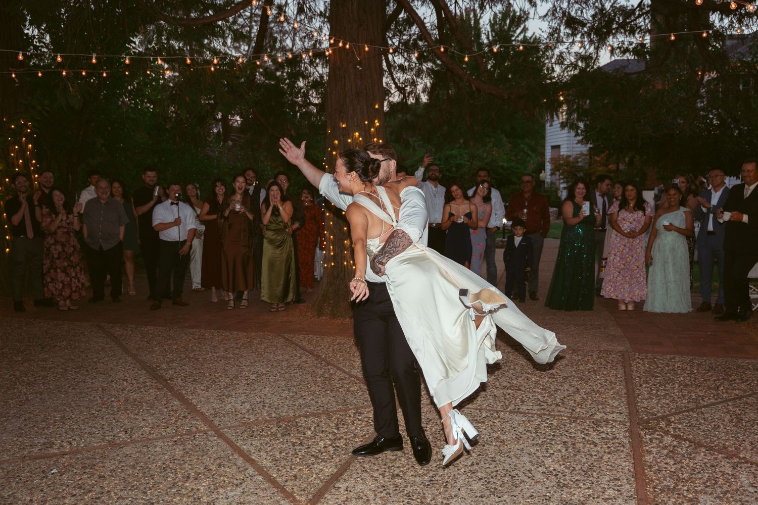 Wedding celebration on a paved outdoor area with guests watching a special moment.
