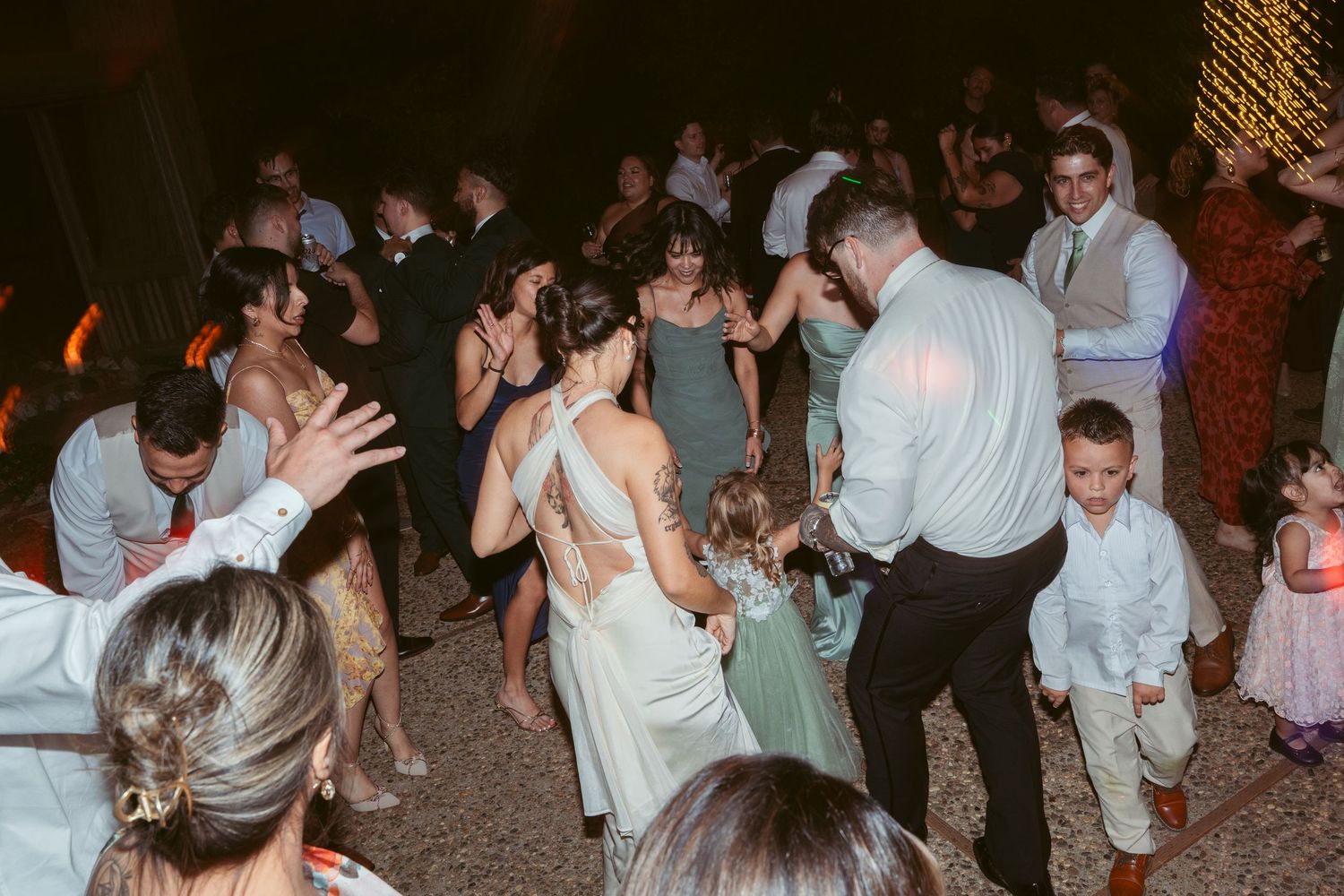 Lively dance floor filled with wedding guests celebrating under ambient lighting.