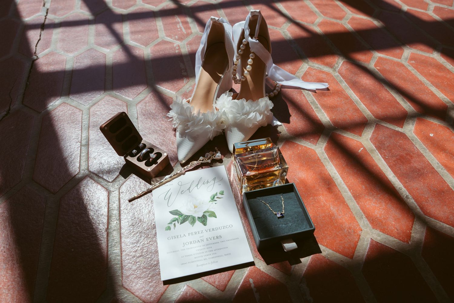 Artistic shadow patterns cast across a red brick surface with scattered objects.