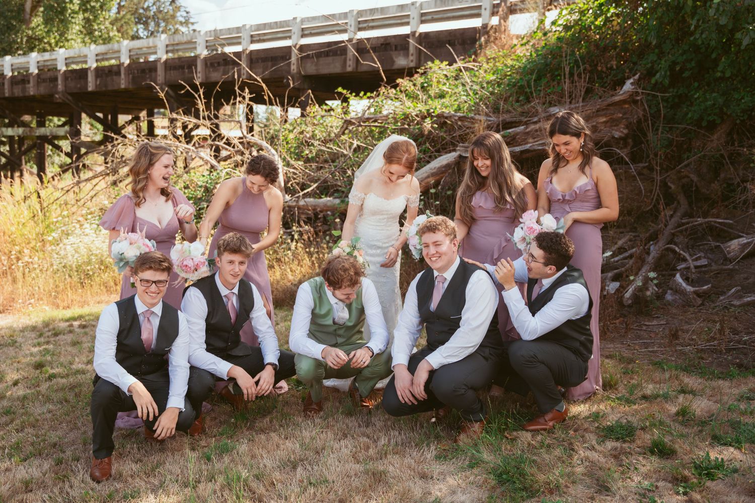 Wedding party lounging together on a hillside in casual poses.