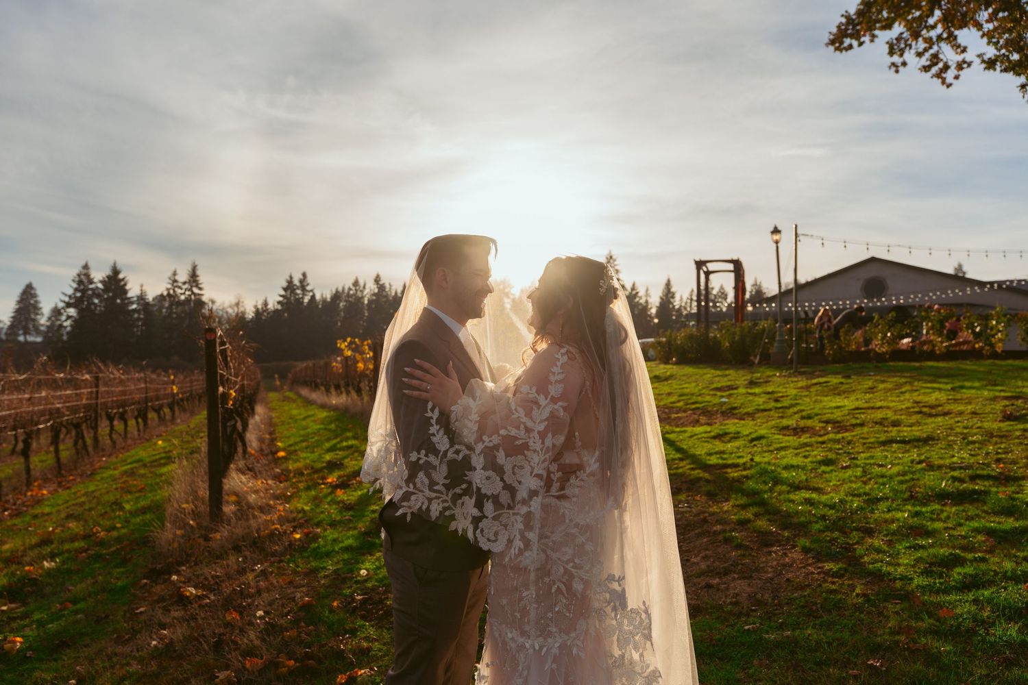 Newlyweds pose in a scenic vineyard setting during golden hour.