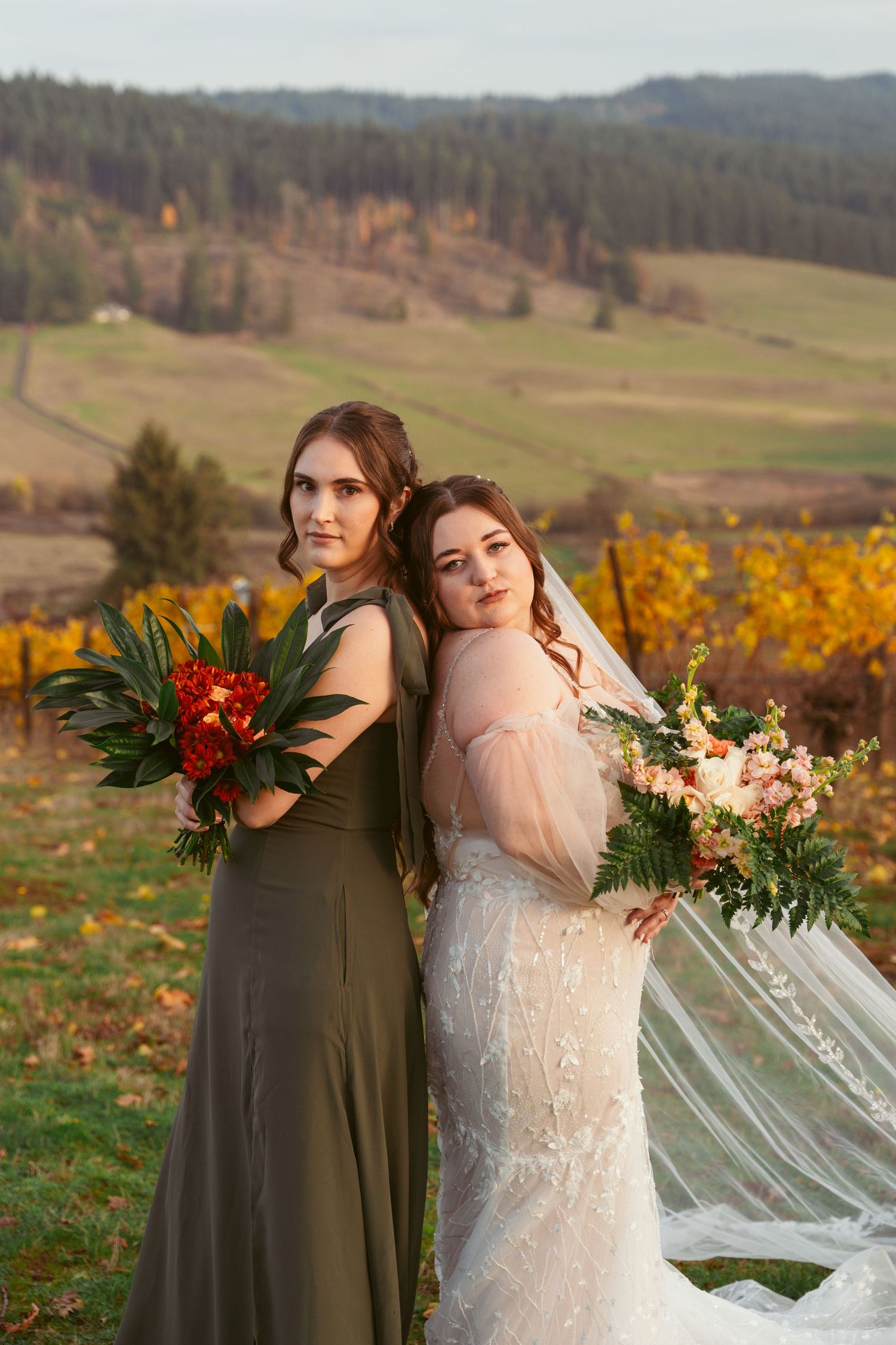 Elegant wedding portrait with autumn vineyard backdrop and flowing veil.