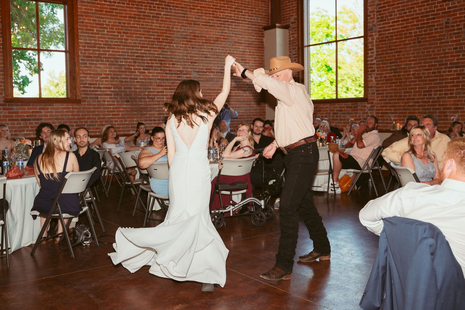 Dancers showcase an elegant spinning move at a wedding reception in a historic brick building.
