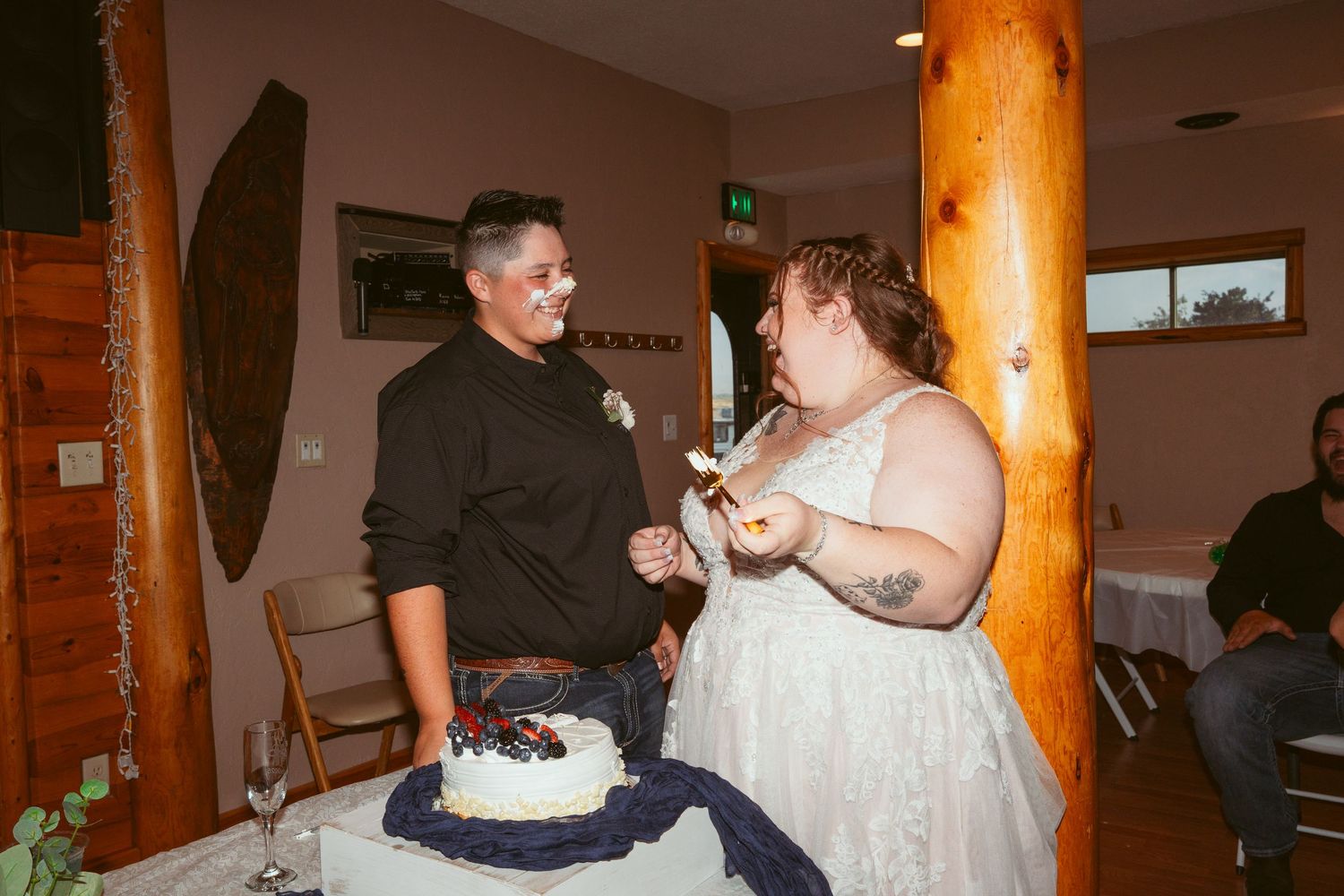 Newlyweds playfully feeding each other cake at their wedding reception.