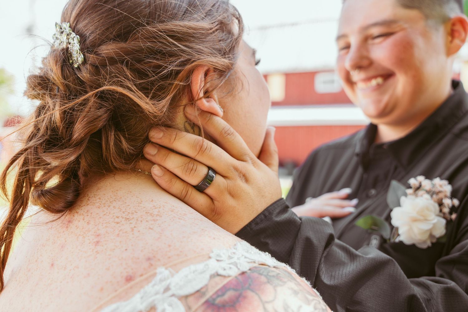 A couple shares a tender kiss during their wedding celebration with flowers and decorative elements in the background.