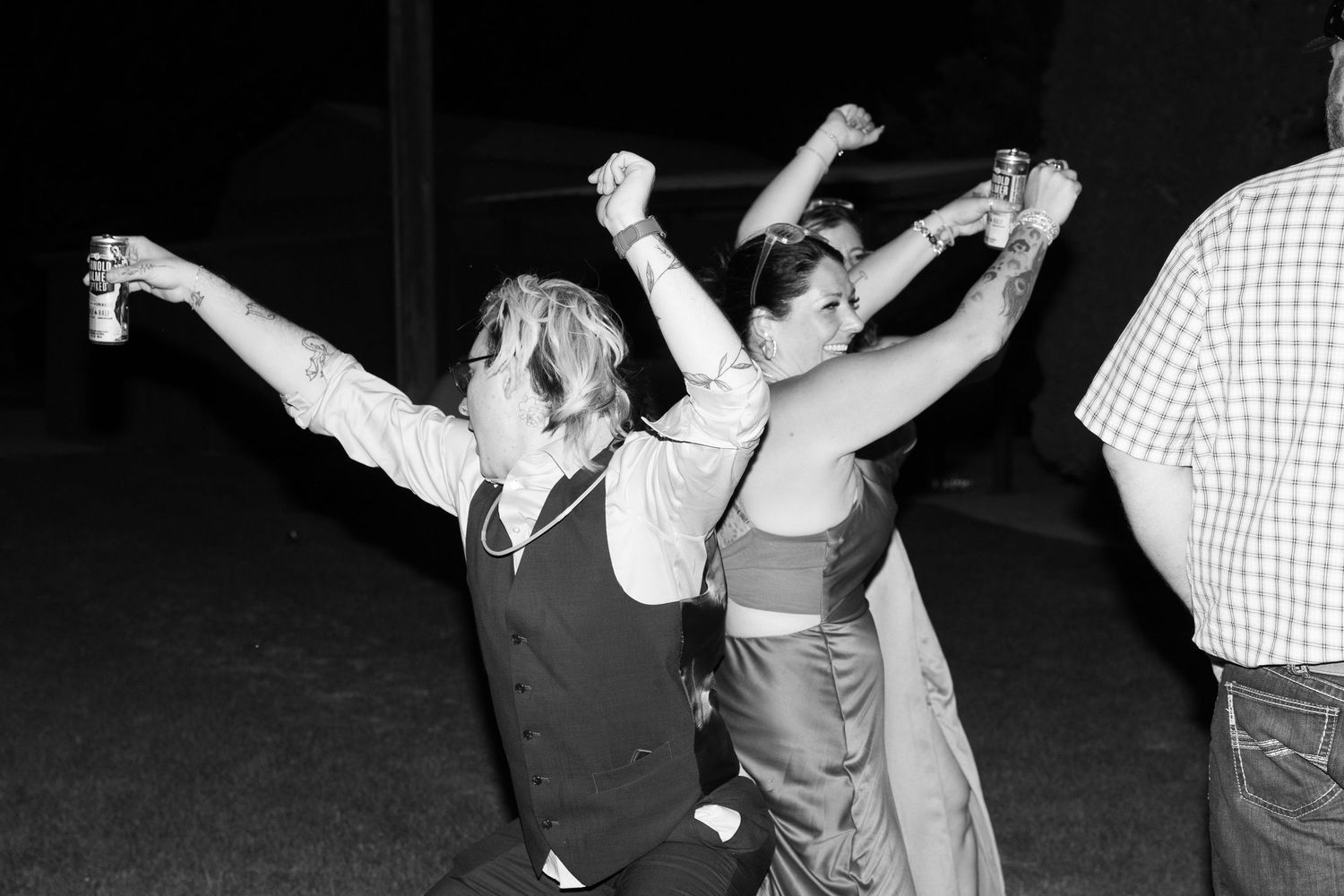 Wedding party members dancing and celebrating during an evening reception.