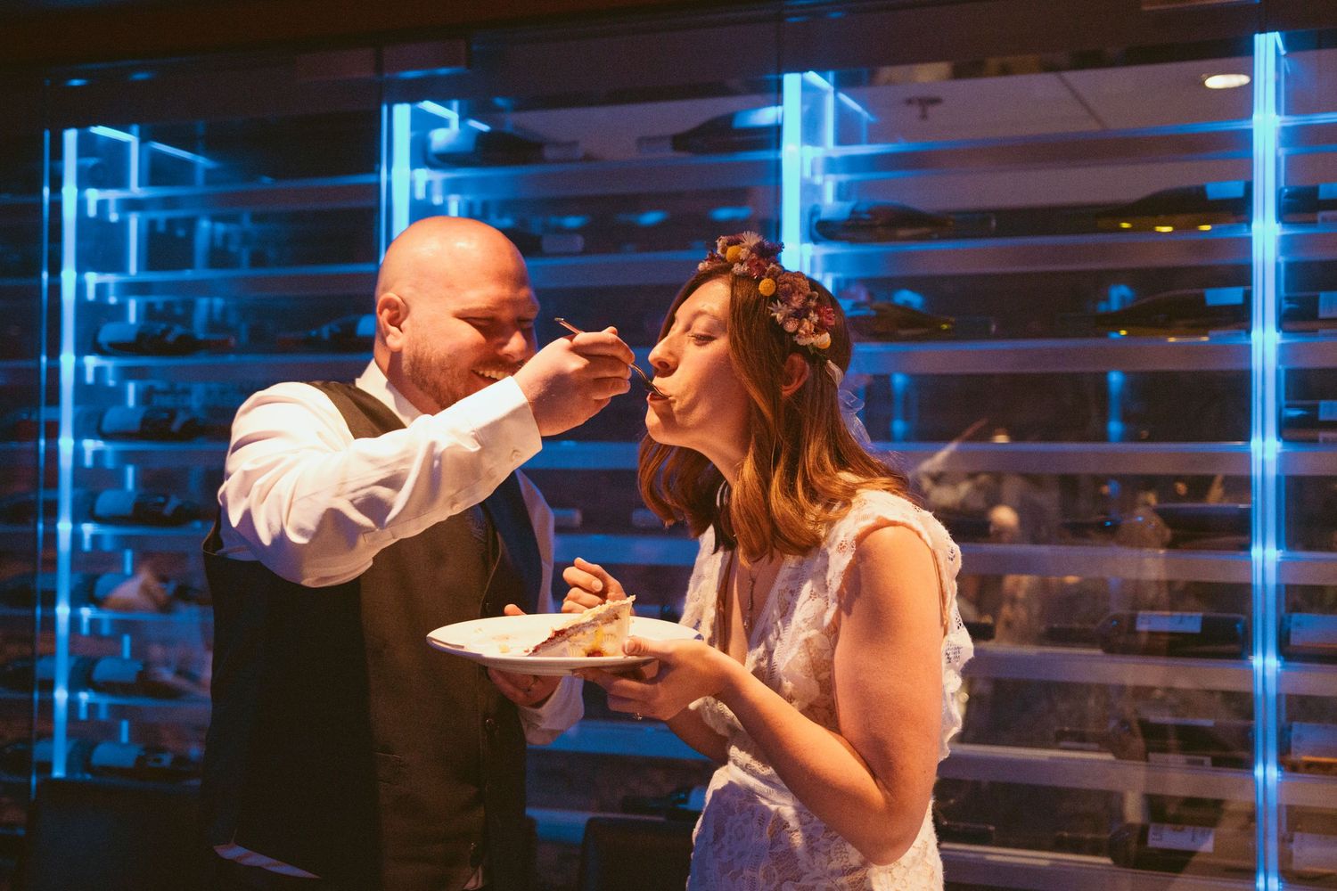 Wedding reception moments captured under modern blue lighting and wooden wall decor.
