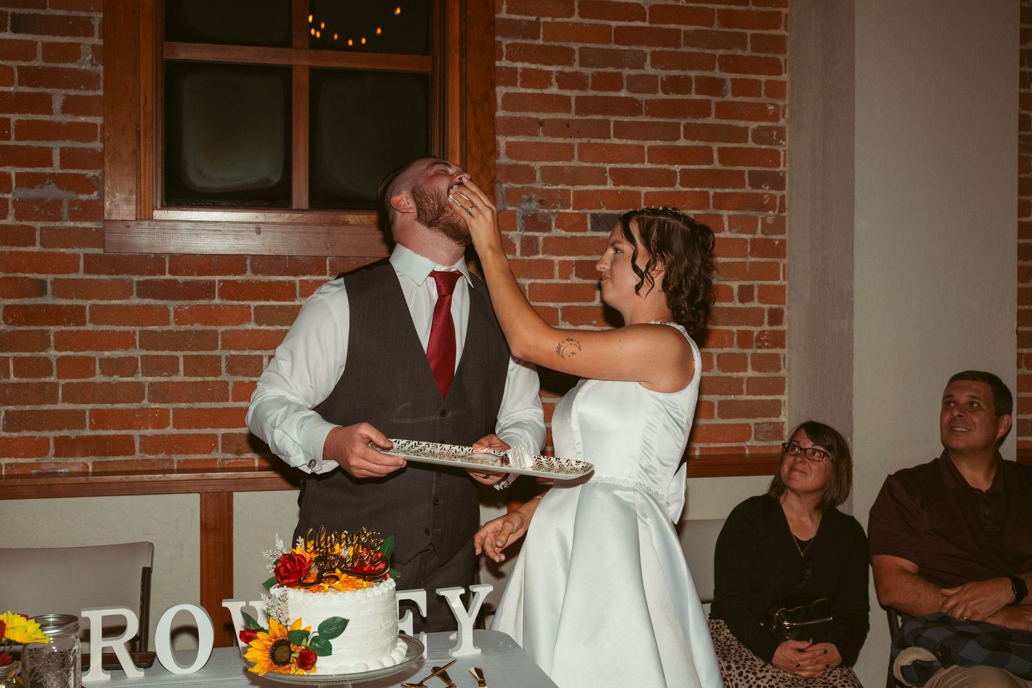 Wedding reception festivities with dancing and cake cutting in a brick-walled space.