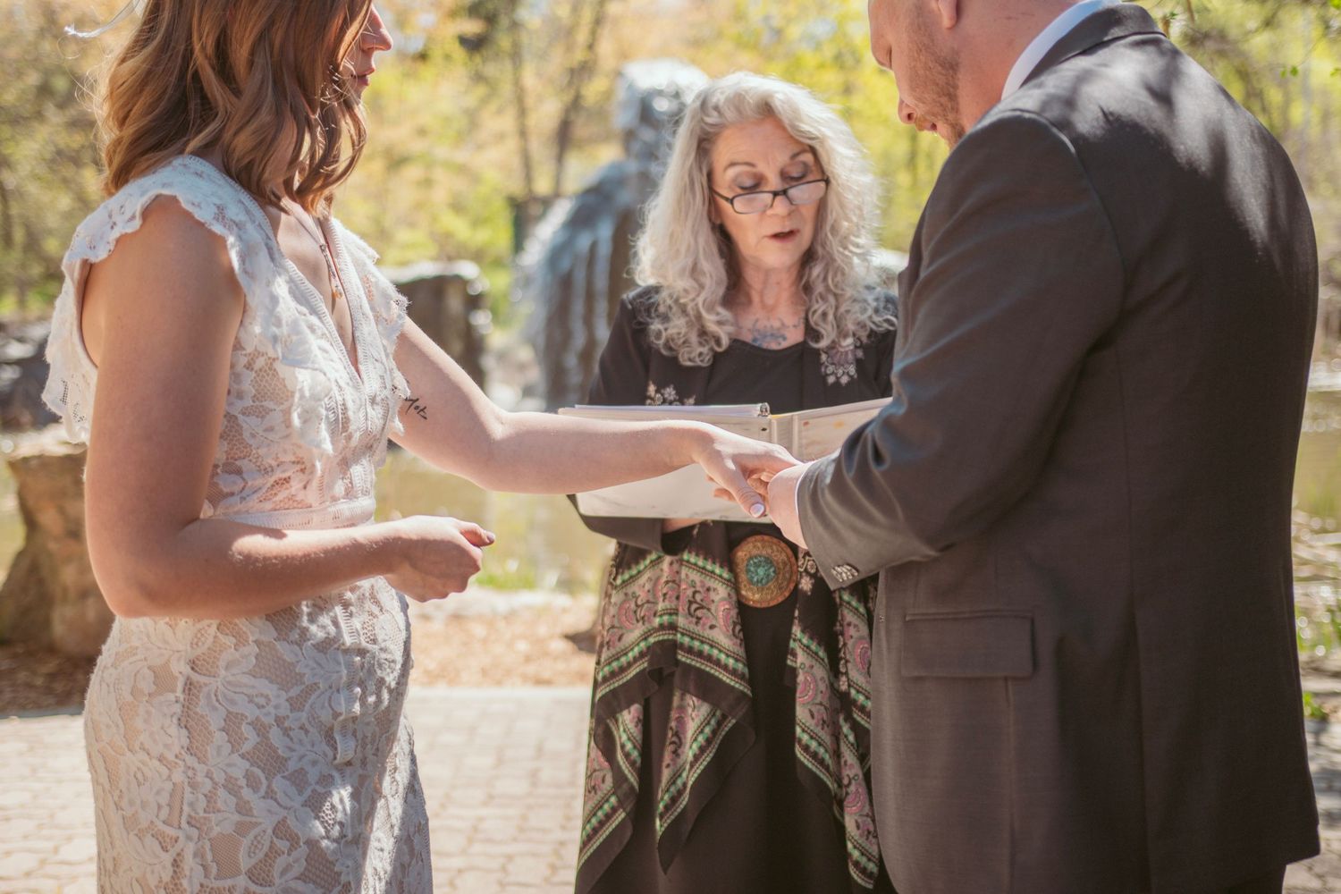 Couple in formal attire poses together during an outdoor wedding photoshoot with natural sunlit backdrop.