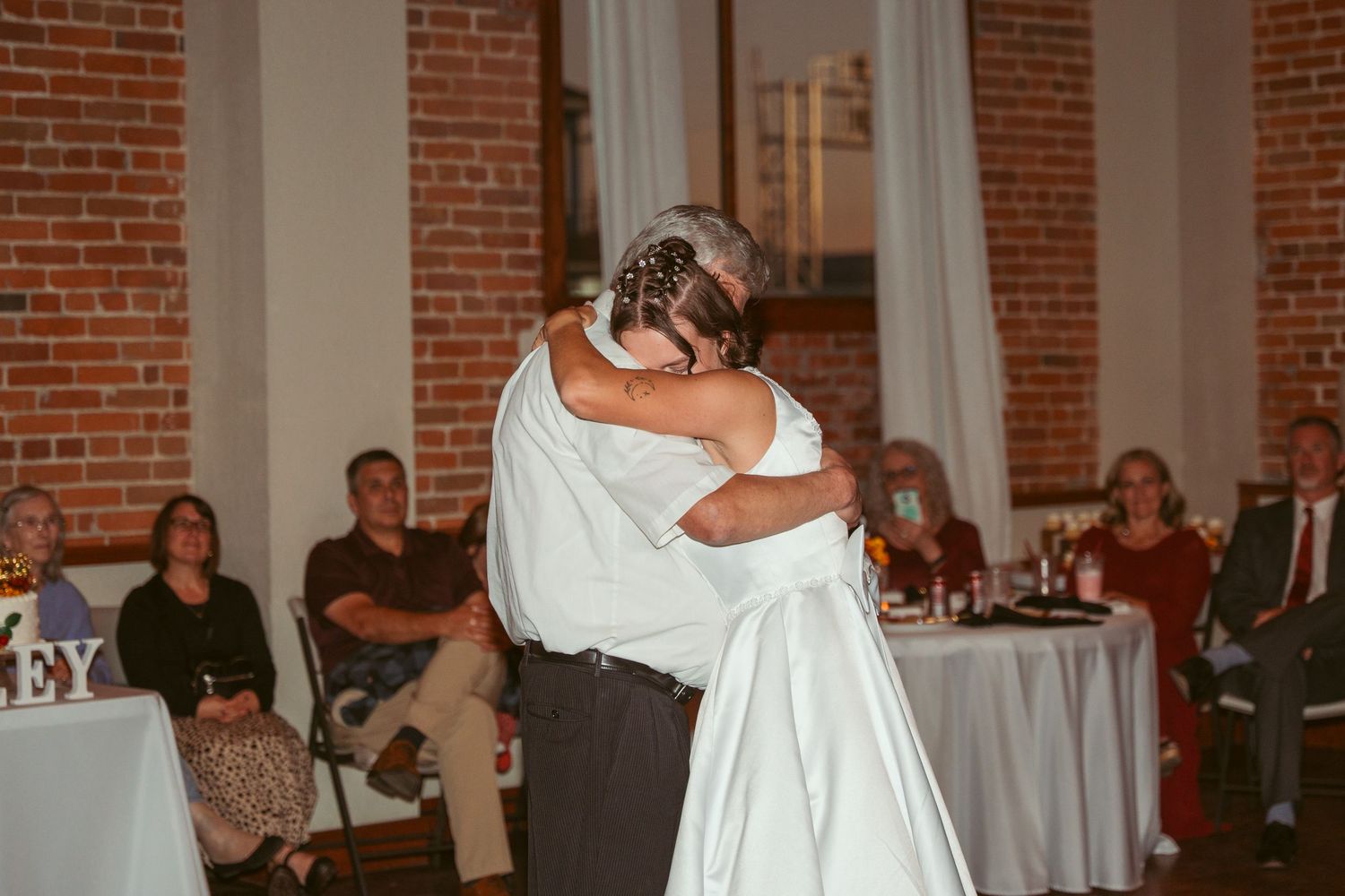 Wedding celebration in an elegant brick venue with white columns and decorative lighting.