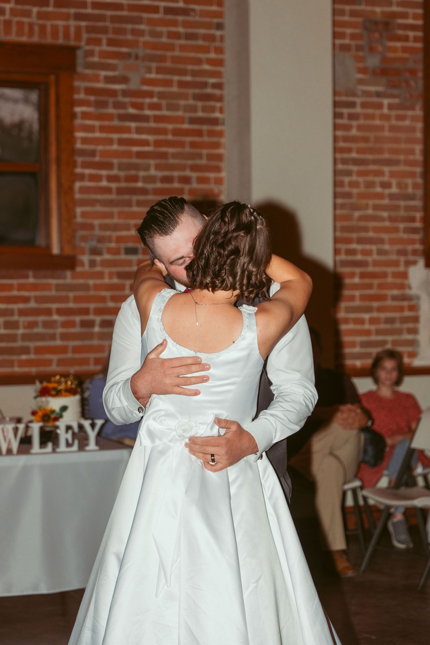 An intimate dance moment at a wedding reception in a brick-walled venue.