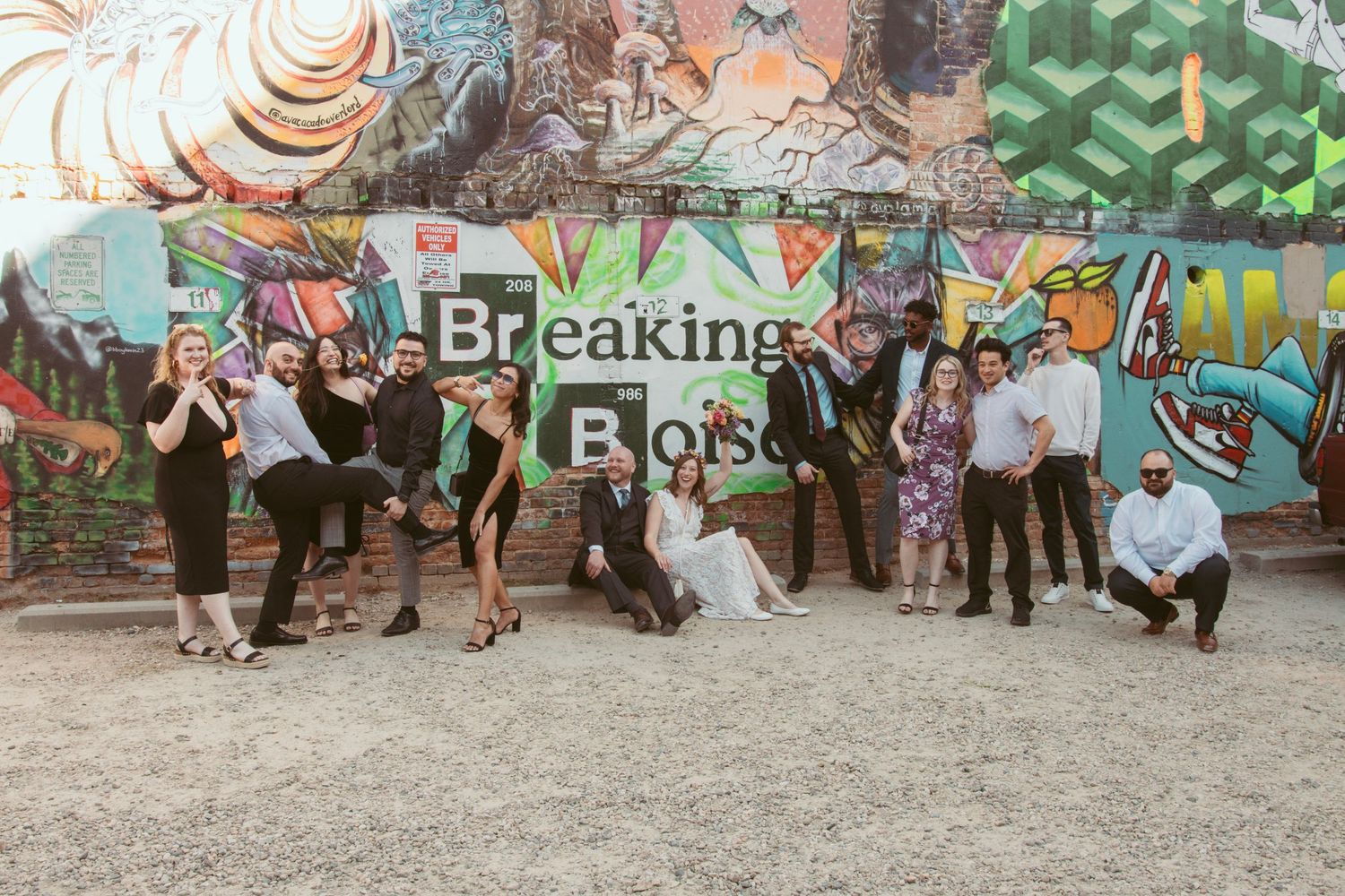 Group photo of wedding party posing casually in front of street art mural.