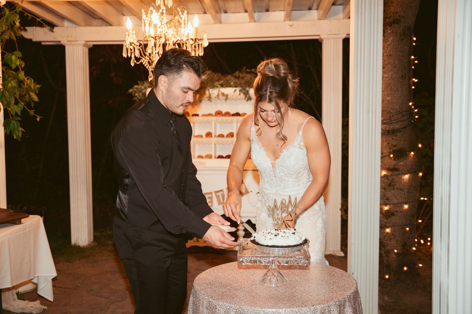 Wedding reception guests dancing and celebrating on an outdoor patio decorated with elegant chandeliers.
