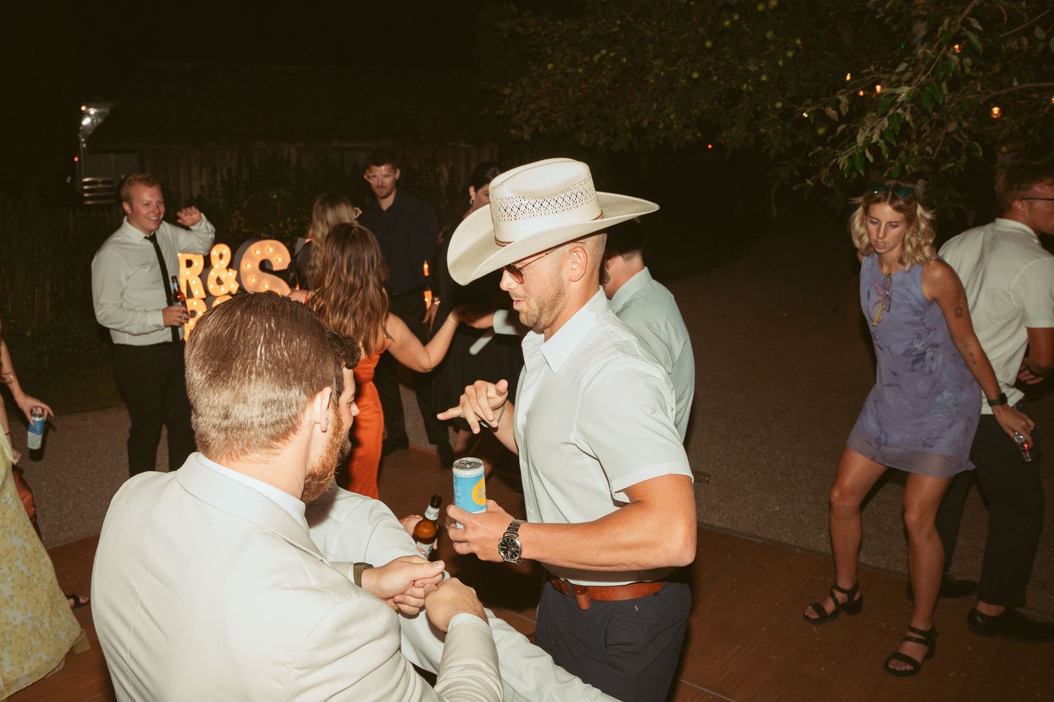 Partygoers dancing and celebrating at an outdoor nighttime event.