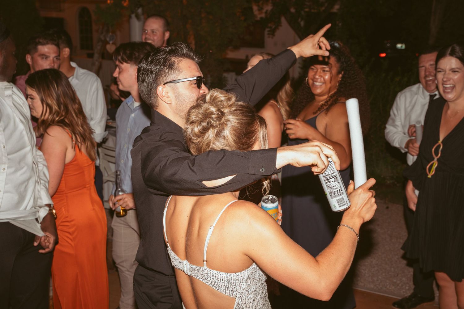 Wedding party dancing and celebrating at a lively outdoor reception.