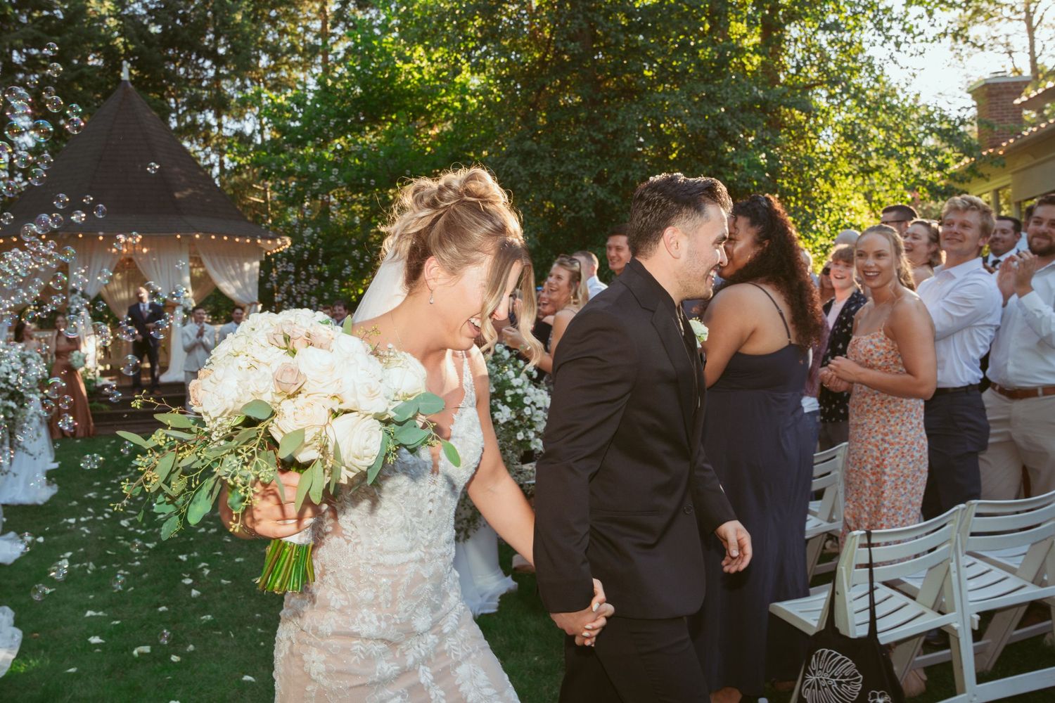 Guests gather on a lawn for a joyful outdoor wedding celebration.