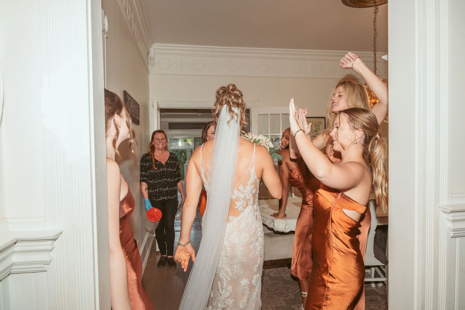 Wedding reception scene with guests in formal attire mingling in an elegant white interior.