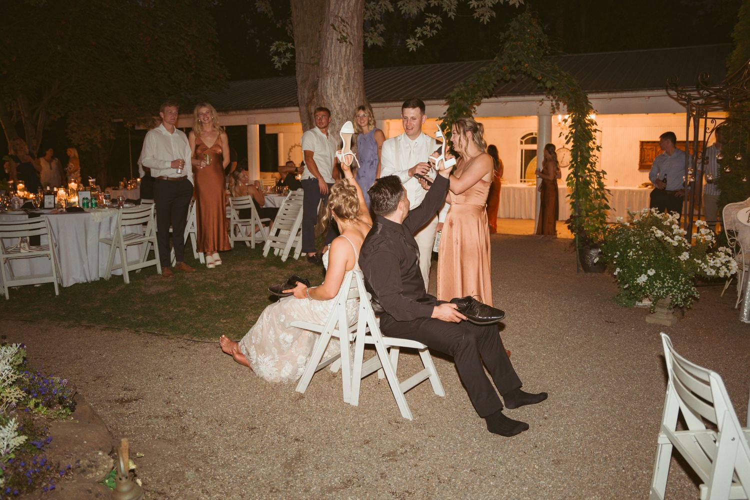 Wedding couple participating in traditional chair dance at outdoor reception.