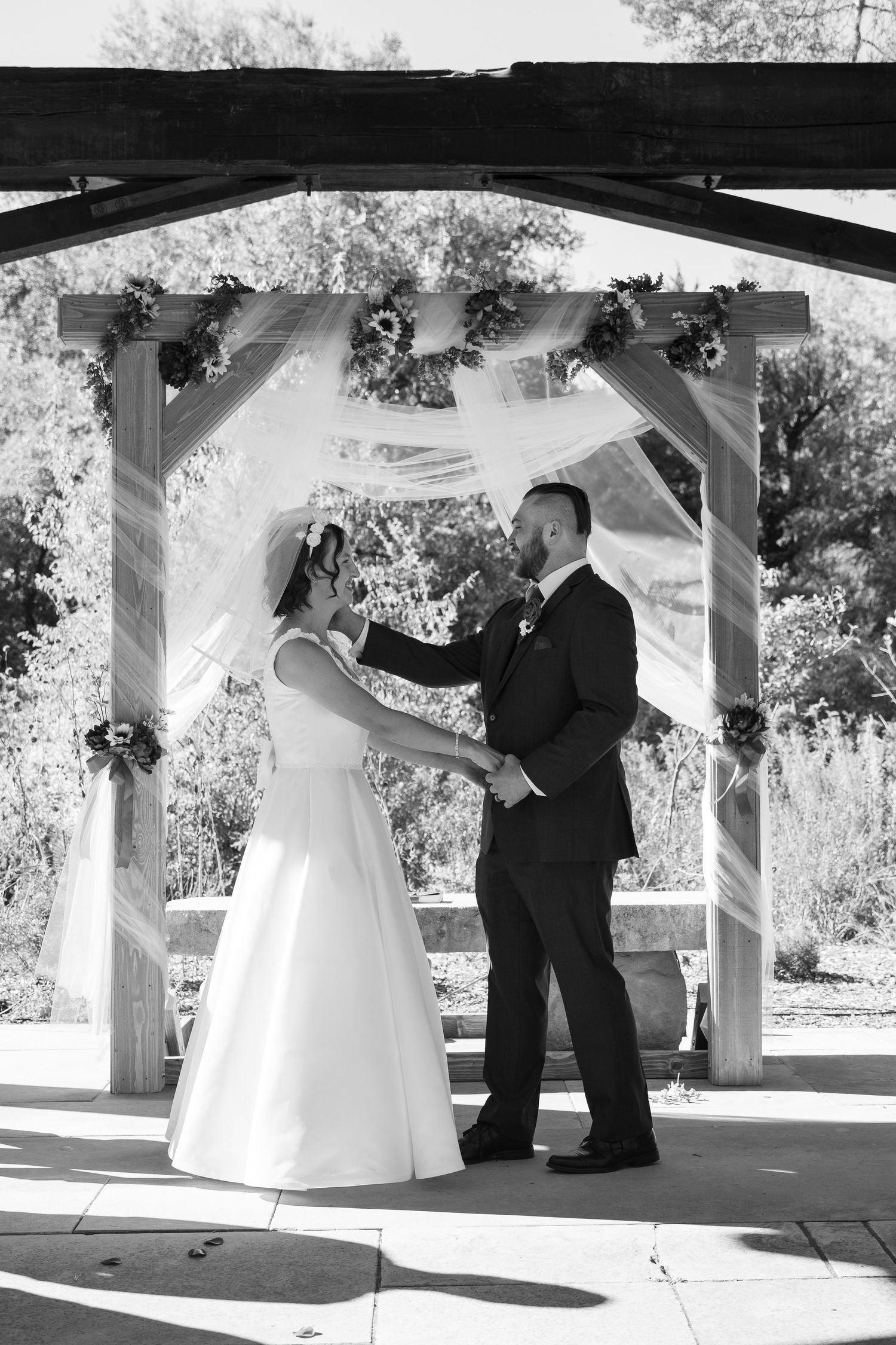 Black and white photo of a wedding ceremony under a decorated pavilion.