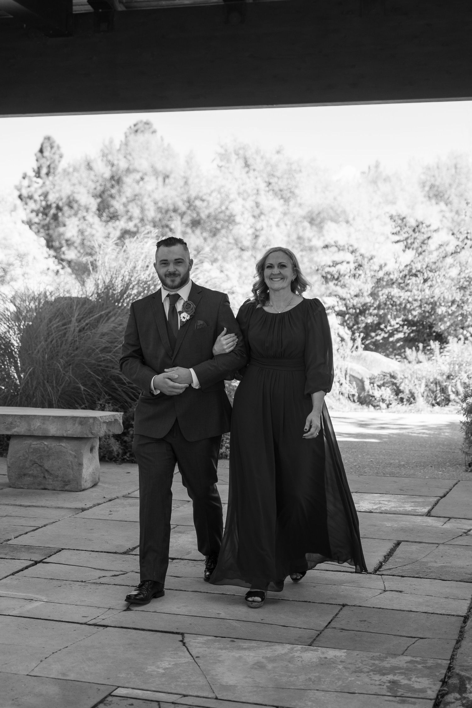 Black and white photo of formal wedding attire on stone pavement during outdoor celebration.