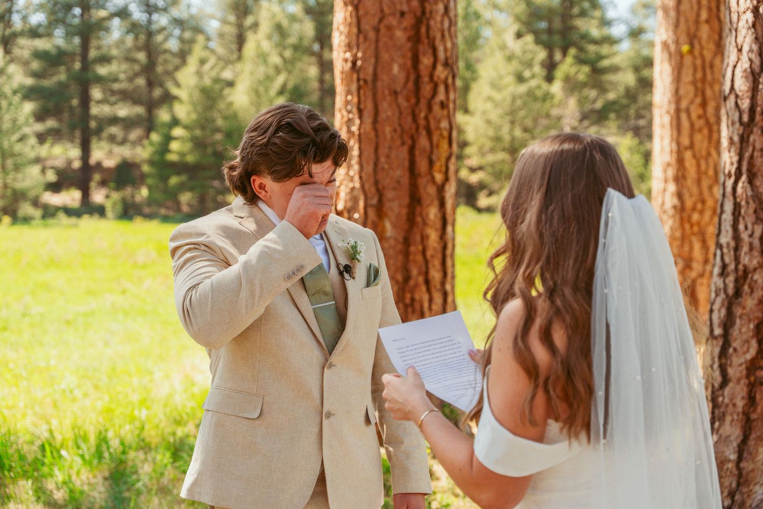 An emotional wedding moment captured between a couple in a natural outdoor setting.