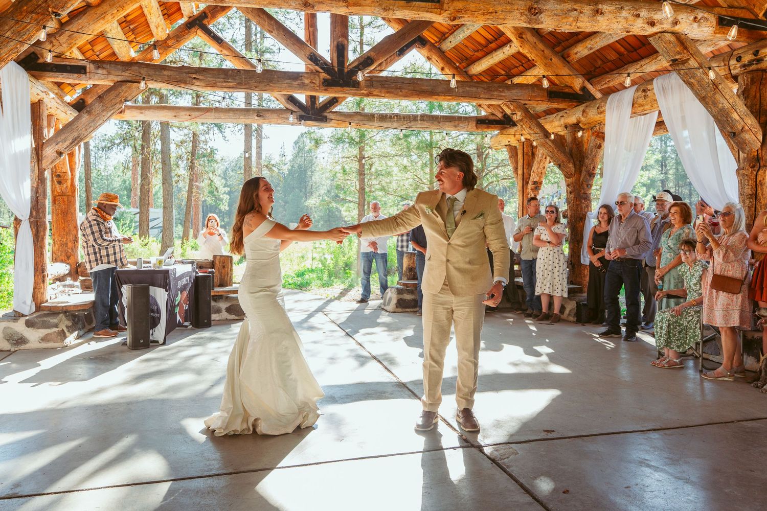 Couple twirls during their wedding dance in a sun-drenched rustic pavilion.